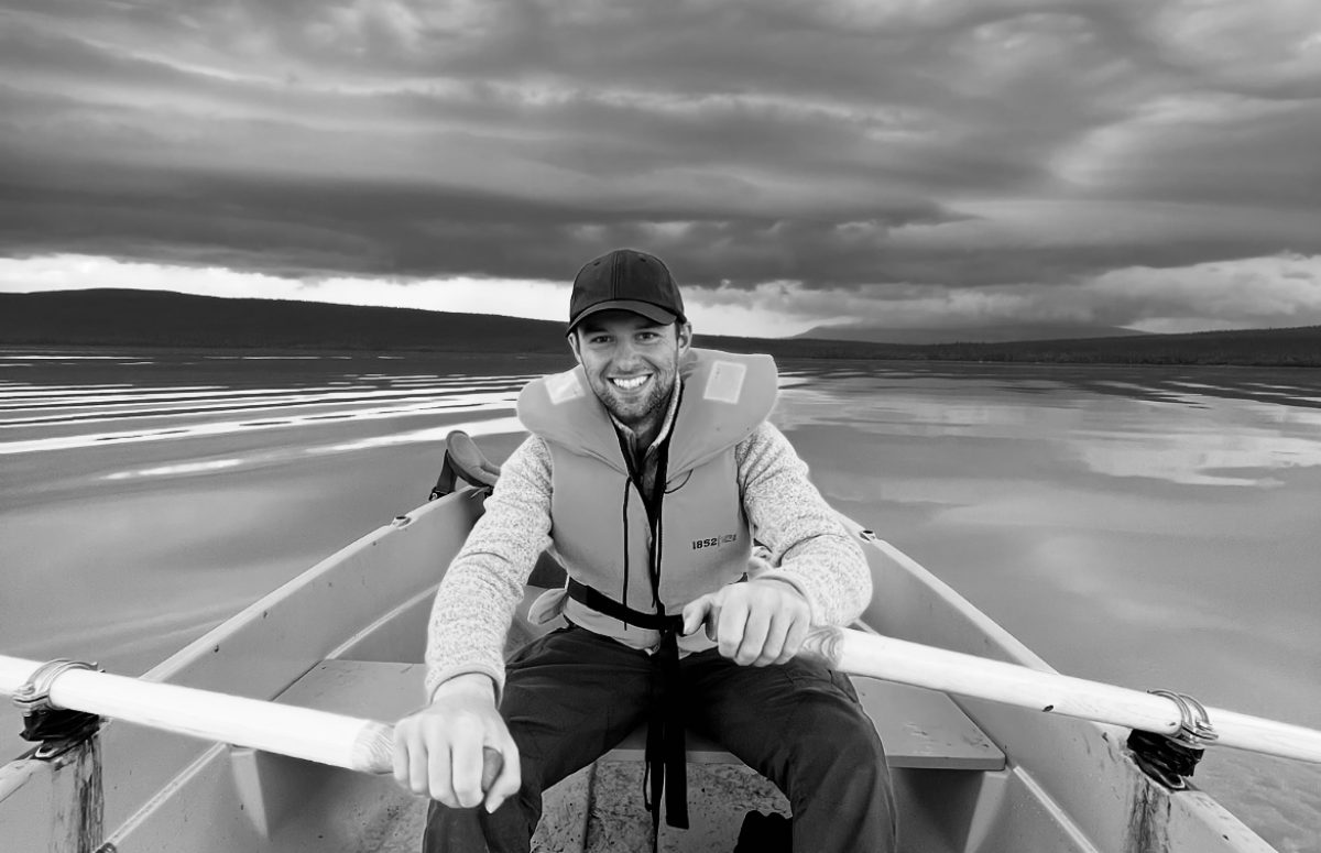 Dominic am rundern auf dem Kungsleden Trail, auf einem See mit Gewitter