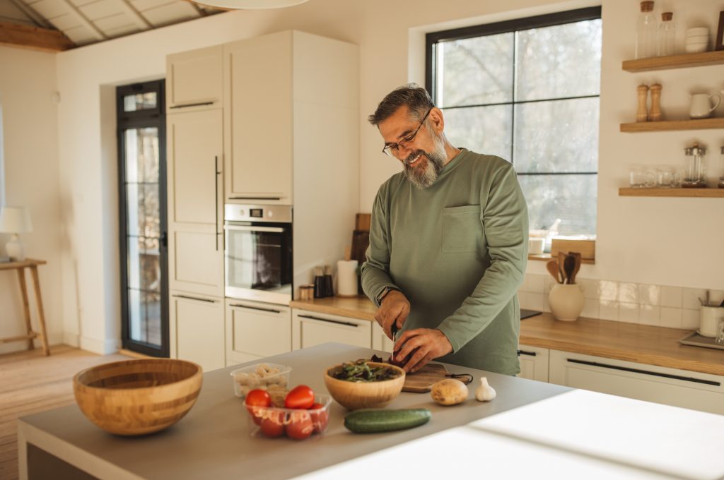 Mature man cooking heathy breakfast at his kitchen at home.